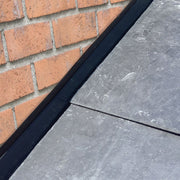 An image of a Permavent Easy Soaker on the edge of a roof between the slates and brick wall t show where it is used.