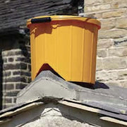 Image of a red gorilla Roofers ridge bucket in yellow perched / sitting on the ridge of a roof.